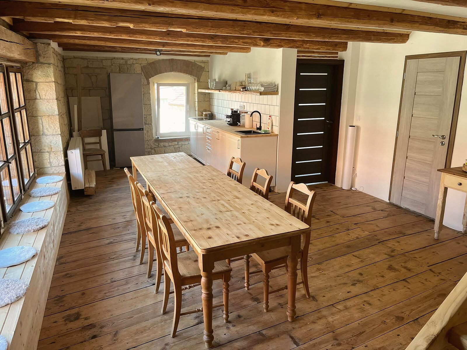 Dlouhý stůl u pískovcové zdi a kuchyňská linka